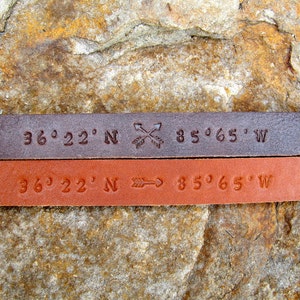 May include: Two leather bracelets with the coordinates 36&deg;22' N 85&deg;65' W engraved on them. One bracelet is brown and the other is a lighter brown.