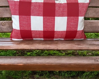 May include: A red and white checkered throw pillow on a wooden bench. The pillow is made of a soft, woven fabric and has a classic buffalo plaid pattern.