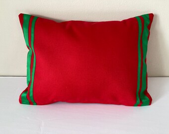 May include: Red pillow with two green stripes along the edges.