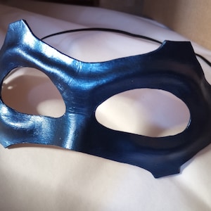 May include: A blue leather masquerade mask with two eye holes and a black elastic band.