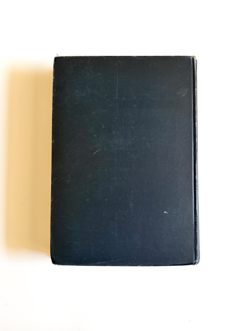 May include: A rectangular, black book with a slightly textured cover. The book is closed and viewed from the top, showing the spine and edges. The cover has minor wear and tear.