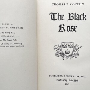 Puede incluir: Una portada de libro con el t&iacute;tulo "The Black Rose" de Thomas B. Costain. La portada presenta una ilustraci&oacute;n en blanco y negro de un escudo de armas con tres coronas.