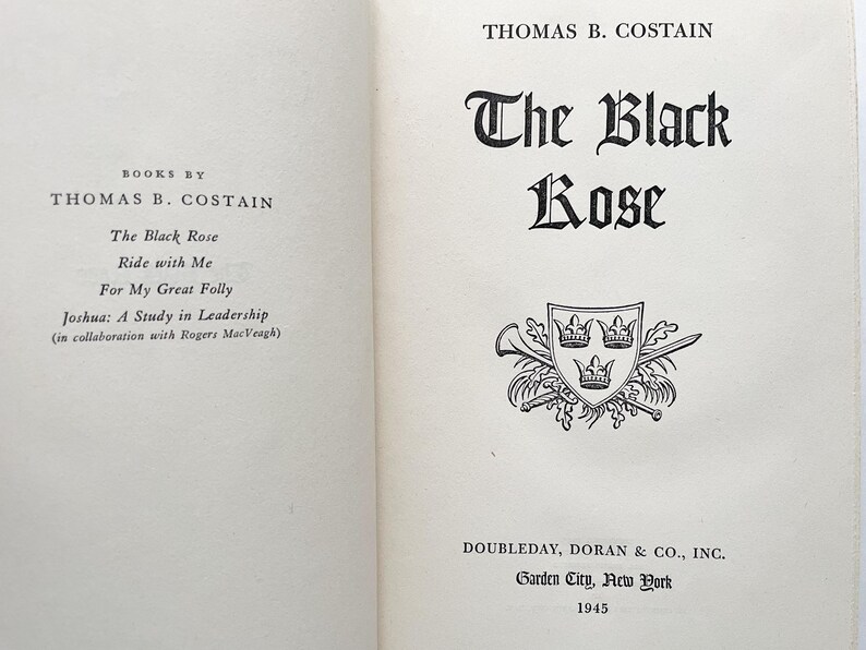 Puede incluir: Una portada de libro con el t&iacute;tulo "The Black Rose" de Thomas B. Costain. La portada presenta una ilustraci&oacute;n en blanco y negro de un escudo de armas con tres coronas.