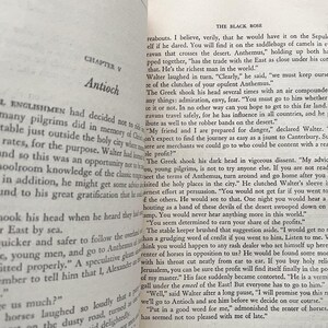 Puede incluir: Una p&aacute;gina de un libro antiguo titulado "La Rosa Negra" con texto sobre un viaje al Este. El texto describe a un mercader llamado Anthemus que controla el comercio con el Este y es conocido por sus caravanas.