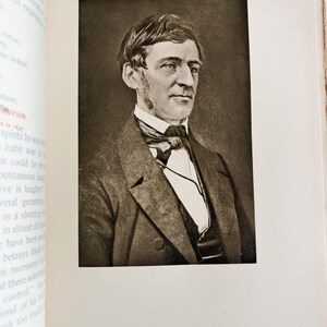 May include: A sepia-toned portrait of a man in a suit and tie, set within a book's pages. The man has short hair and a serious expression. The book's pages are off-white, with text visible on the left side.