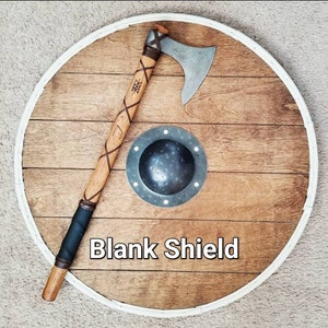 May include: A wooden shield with a white border, a metal axe, and a small metal shield. The axe has a wooden handle wrapped with leather. The text "Blank Shield" is displayed on the shield.