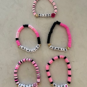 May include: Five pink, black, and white beaded bracelets with the names "BLINK", "LALISA", "JENNIE", "JISOO", and "ROSE" spelled out in white letters. Each bracelet has a small gold charm.