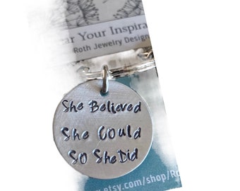 May include: Silver keychain with a round charm that reads "She Believed She Could So She Did".