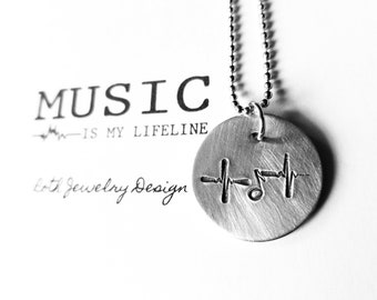May include: A silver necklace with a round pendant featuring a musical note and a heartbeat graphic. The pendant is engraved with the text "MUSIC IS MY LIFELINE".