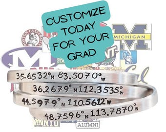 May include: Silver metal cuff bracelets engraved with latitude and longitude coordinates. The bracelets are stacked, with the text "CUSTOMIZE TODAY FOR YOUR GRAD" in a turquoise bubble above. University logos are in the background.