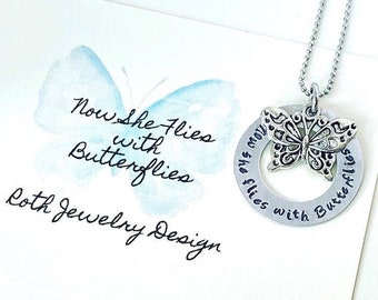 May include: Silver necklace with a butterfly charm and a round pendant engraved with the words "Now she flies with butterflies".