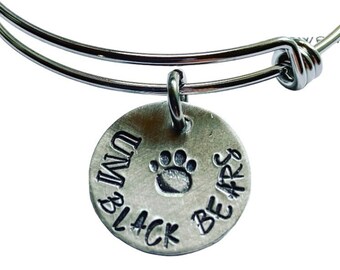 May include: Silver charm bracelet with a round charm that says "I'm Black Bears" with a paw print in the center.