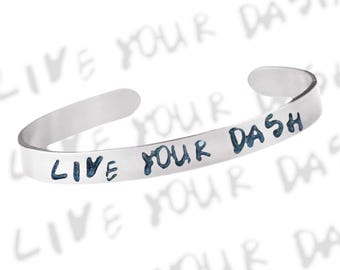 May include: Silver bracelet with the words "Live Your Dash" engraved on it.
