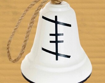 May include: White ceramic bell with a black geometric design and a brown rope handle.