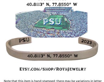 May include: A silver-colored cuff bracelet with the text "PSU", "2023", and coordinates 40.8113° N, 77.8550° W. The image also includes an illustration of Beaver Stadium and the text "Beaver Stadium Coordinates".