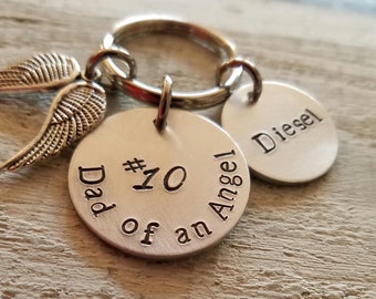 May include: Silver keychain with three charms. The largest charm is round and says "Dad of an Angel #10". The second charm is round and says "Diesel". The third charm is a pair of angel wings.