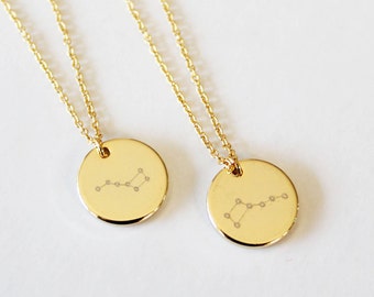 May include: Two gold necklaces with round pendants featuring a constellation design. The pendants are engraved with a constellation of stars.