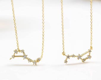 May include: Two gold necklaces with a constellation design. Each necklace features a delicate chain and a pendant shaped like a constellation with small, clear stones.