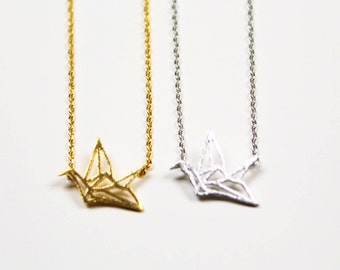 Peut inclure: Deux colliers délicats avec des pendentifs en forme de grue origami. L'un a une grue dorée, l'autre une grue argentée.