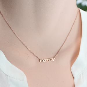 Puede incluir: Un collar de oro con la palabra "mam&aacute;" escrita en una fuente delicada.