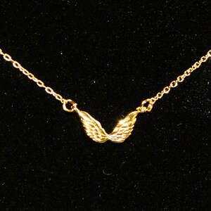 Op de afbeelding: Een gouden ketting met een klein hanger in de vorm van engelenvleugels.