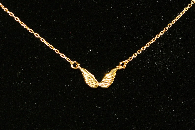 Op de afbeelding: Een gouden ketting met een klein hanger in de vorm van engelenvleugels.