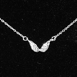 Op de afbeelding: Een zilveren ketting met een klein, gedetailleerd engelenvleugel hanger.