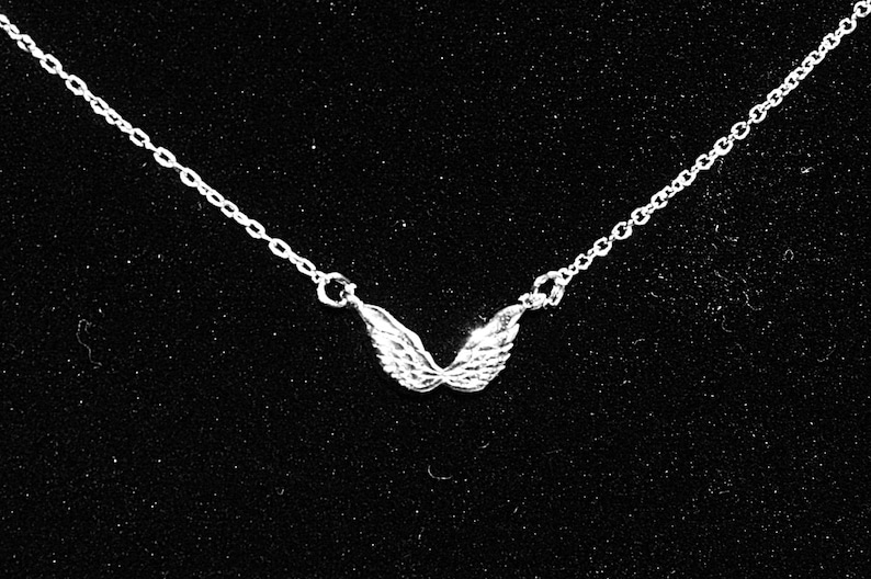 Op de afbeelding: Een zilveren ketting met een klein, gedetailleerd engelenvleugel hanger.