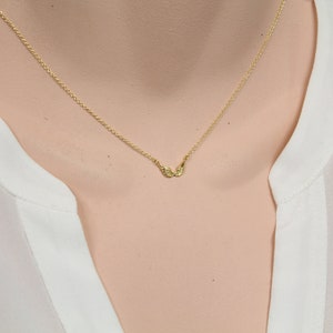 May include: A delicate gold chain necklace with a small, winged pendant.