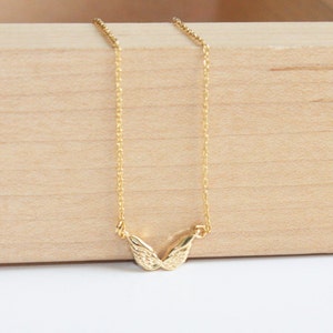 May include: A gold chain necklace with a delicate, textured, wing-shaped pendant.