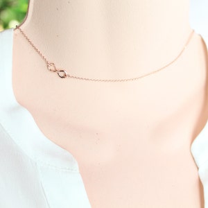 May include: A delicate rose gold necklace with an infinity symbol pendant.