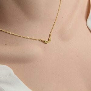 May include: A delicate gold chain necklace with a small pair of angel wings pendant.