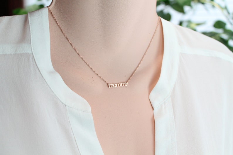 Puede incluir: Un collar de oro con la palabra "mam&aacute;" escrita en una fuente delicada.