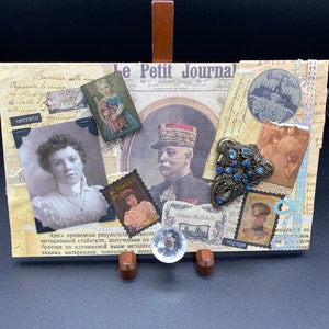 May include: A vintage-style collage featuring a variety of images and ephemera, including a newspaper clipping, a photograph of a woman, a photograph of a man in a military uniform, and a photograph of a young girl. The collage is decorated with a variety of embellishments, including a brooch, a button, and a piece of lace. The text "Le Petit Journal" is visible in the upper right corner of the collage.