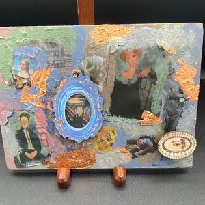 May include: A mixed media collage artwork featuring various images, including a woman in a blue dress, a painting of The Scream, and a woman with a pearl earring. The artwork is framed with a wooden easel and has a textured, layered surface.