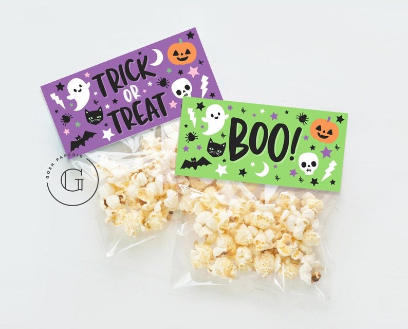May include: Two Halloween-themed treat bags with purple and green labels. The purple label says "Trick or Treat" with a ghost, cat, and pumpkin. The green label says "Boo!" with a ghost, cat, and pumpkin. Both labels have stars, bats, and other Halloween-themed graphics.