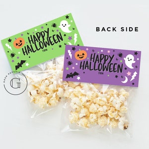 May include: Two Halloween-themed gift bags with popcorn inside. The bags have purple and green tags with the text "Happy Halloween" and a space for "From". The tags are decorated with ghosts, pumpkins, bats, and stars.