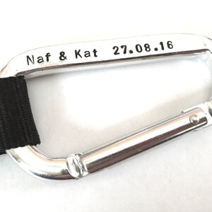 May include: Silver carabiner with a black strap and the inscription "Naf & Kat 27.08.16".
