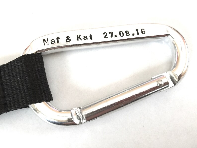 May include: Silver carabiner with a black strap and the inscription "Naf & Kat 27.08.16".