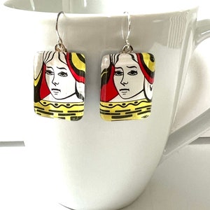 May include: A pair of silver earrings with glass squares featuring the Queen of Hearts playing card design.