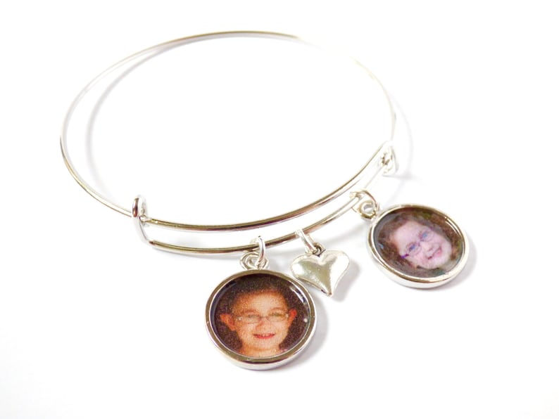 Puede incluir: Un brazalete expandible de plata con dos dijes redondos con fotos y un dije en forma de coraz&oacute;n. Los dijes con fotos muestran im&aacute;genes de primer plano de ni&ntilde;os.