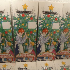 May include: Four packages of silver tinsel Christmas tree garland with a Christmas tree and children on the front. The packages have the text "Qualitäts-Stanniol-Lametta" on the front.