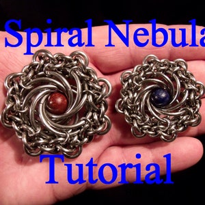 May include: Two silver metal spiral nebula jewellery pieces with a red and a blue stone in the centre. The jewellery pieces are on a hand. The text "Spiral Nebula Tutorial" is above the jewellery pieces.