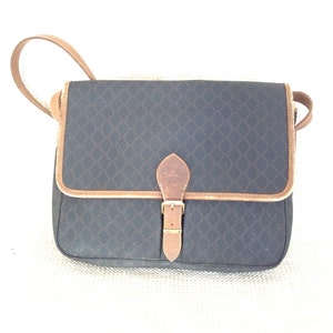 May include: A black and brown leather shoulder bag with a gold buckle. The bag has a geometric pattern.