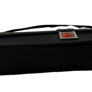 May include: Black rectangular handbag with a flap closure and a shoulder strap. The bag features a silver-toned clasp with a rectangular, orange-red accent. The bag is made of a textured fabric.