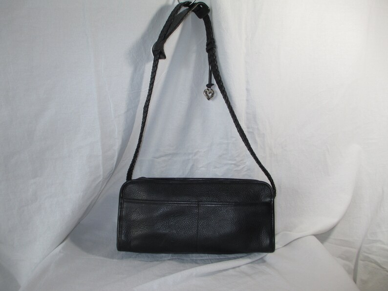 May include: A black leather shoulder bag with a braided strap and a silver heart charm.