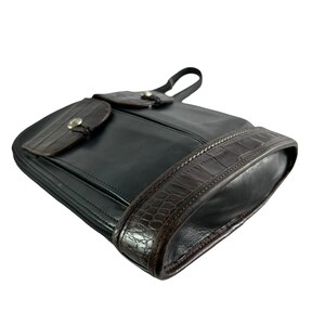 May include: Black leather shoulder bag with a brown crocodile-textured trim and accents. The bag features a flap closure with a silver-tone button and a small handle. The bag is designed with a zipper closure.