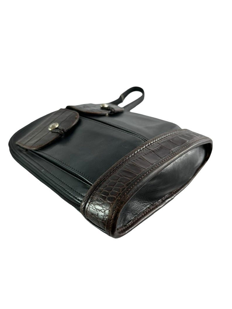 May include: Black leather shoulder bag with a brown crocodile-textured trim and accents. The bag features a flap closure with a silver-tone button and a small handle. The bag is designed with a zipper closure.
