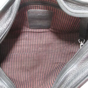 May include: Black leather travel bag with a zipper closure and a red and black striped lining. The bag has a label inside that reads "No. 184594".