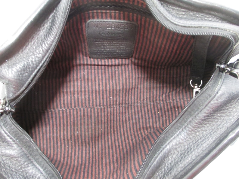 May include: Black leather travel bag with a zipper closure and a red and black striped lining. The bag has a label inside that reads "No. 184594".
